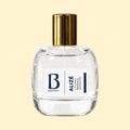 A studio product photograph of a clear glass perfume bottle filled with pale yellow-green fragrance, topped with a reflective gold cylindrical cap and set against a soft cream background. A white label on the front displays the Parfums Berry logo and the name “Flavia Romana Durante.” The transparent bottle reveals the light-coloured perfume, while soft reflections on the glass emphasise its rounded, sculptural shape.