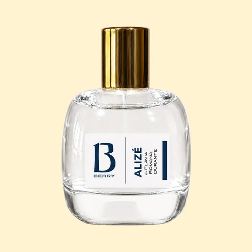 A studio product photograph of a clear glass perfume bottle filled with pale yellow-green fragrance, topped with a reflective gold cylindrical cap and set against a soft cream background. A white label on the front displays the Parfums Berry logo and the name “Flavia Romana Durante.” The transparent bottle reveals the light-coloured perfume, while soft reflections on the glass emphasise its rounded, sculptural shape.