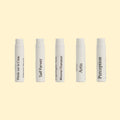 A studio product photograph showing five white perfume sample spray vials arranged in a horizontal row against a soft cream background. Each vial is labeled with a fragrance name from the Centifolia Impressionnée collection, including Pétale sur la Cime, Grace, Caprifoglio Nero, Artis, and Perception. The minimalist vials feature black typography and are evenly spaced, highlighting the discovery set format.