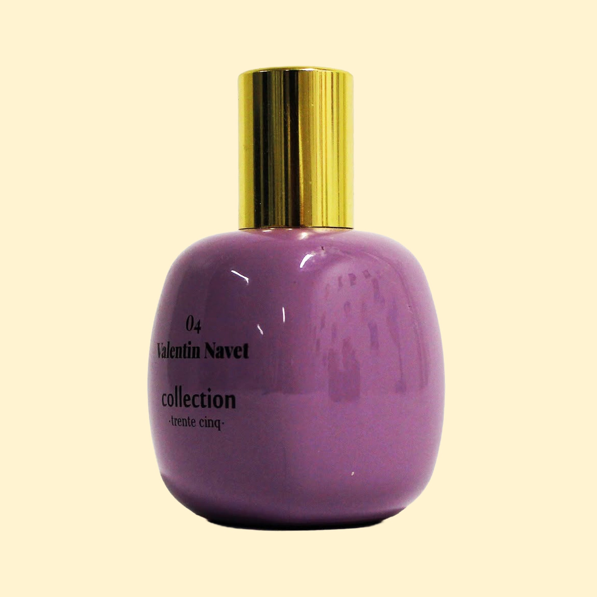 A studio product photograph of a rounded lavender-purple perfume bottle with a reflective gold cylindrical cap, set against a soft cream background. Black text on the bottle reads “04 Valentin Navet” and “collection ·trente cinq·”. The bottle has a glossy, curved surface with soft reflections that accentuate its sculptural shape.