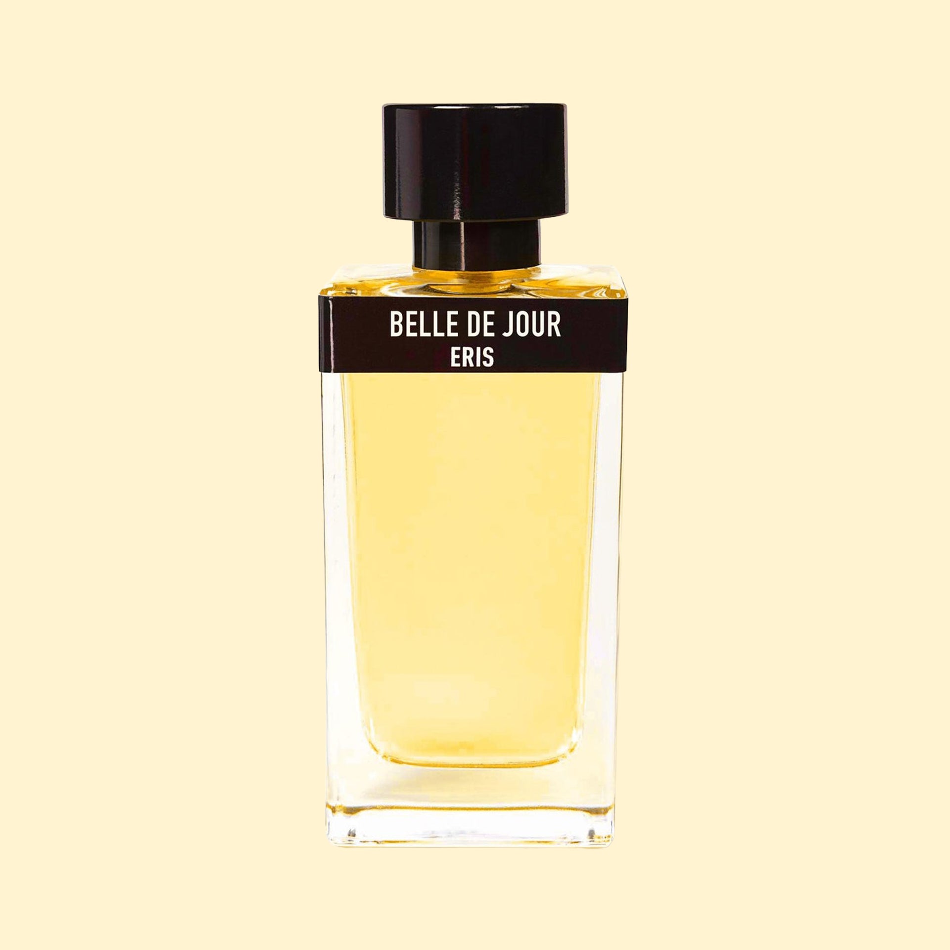 Belle de Jour by ERIS Parfums in a clear glass perfume bottle with pale golden fragrance, black label and black cap against a cream background.