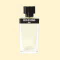 Delta of Venus by ERIS Parfums in a clear glass perfume bottle with pale yellow fragrance and black cap against a cream background.