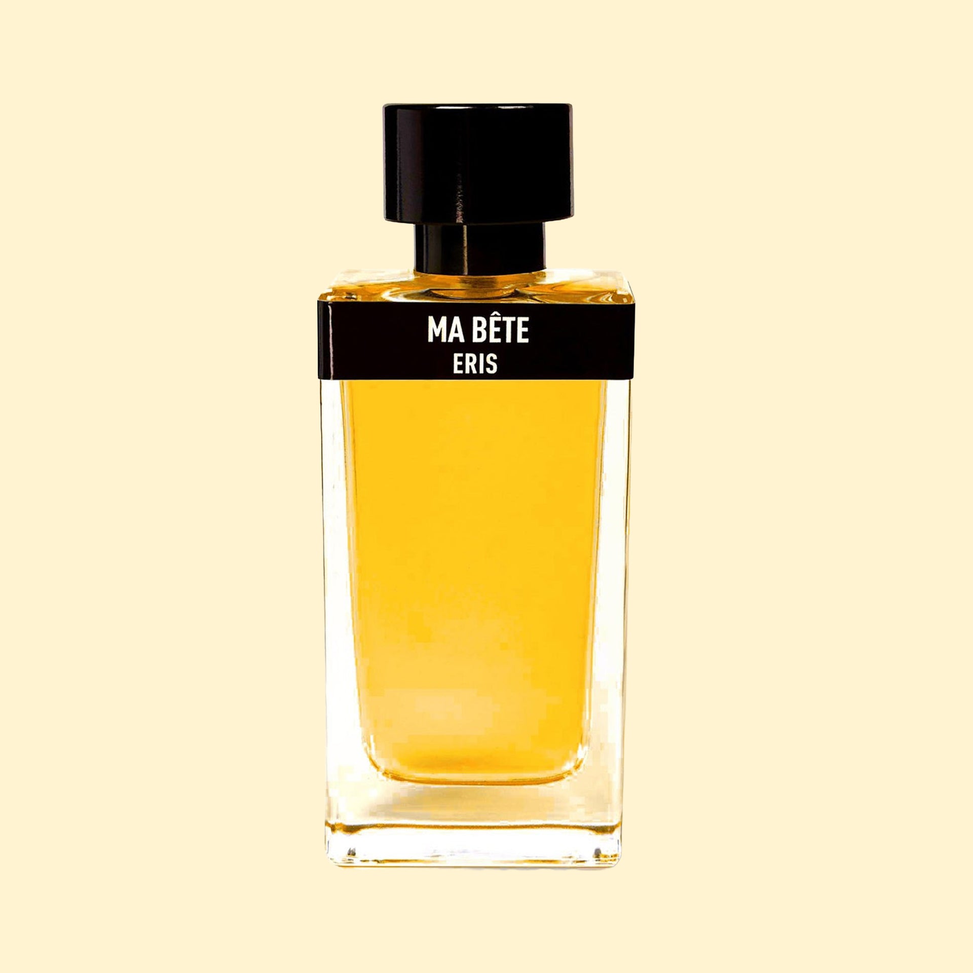 Ma Bête by ERIS Parfums in a clear glass perfume bottle with golden fragrance, black label and black cap against a cream background.