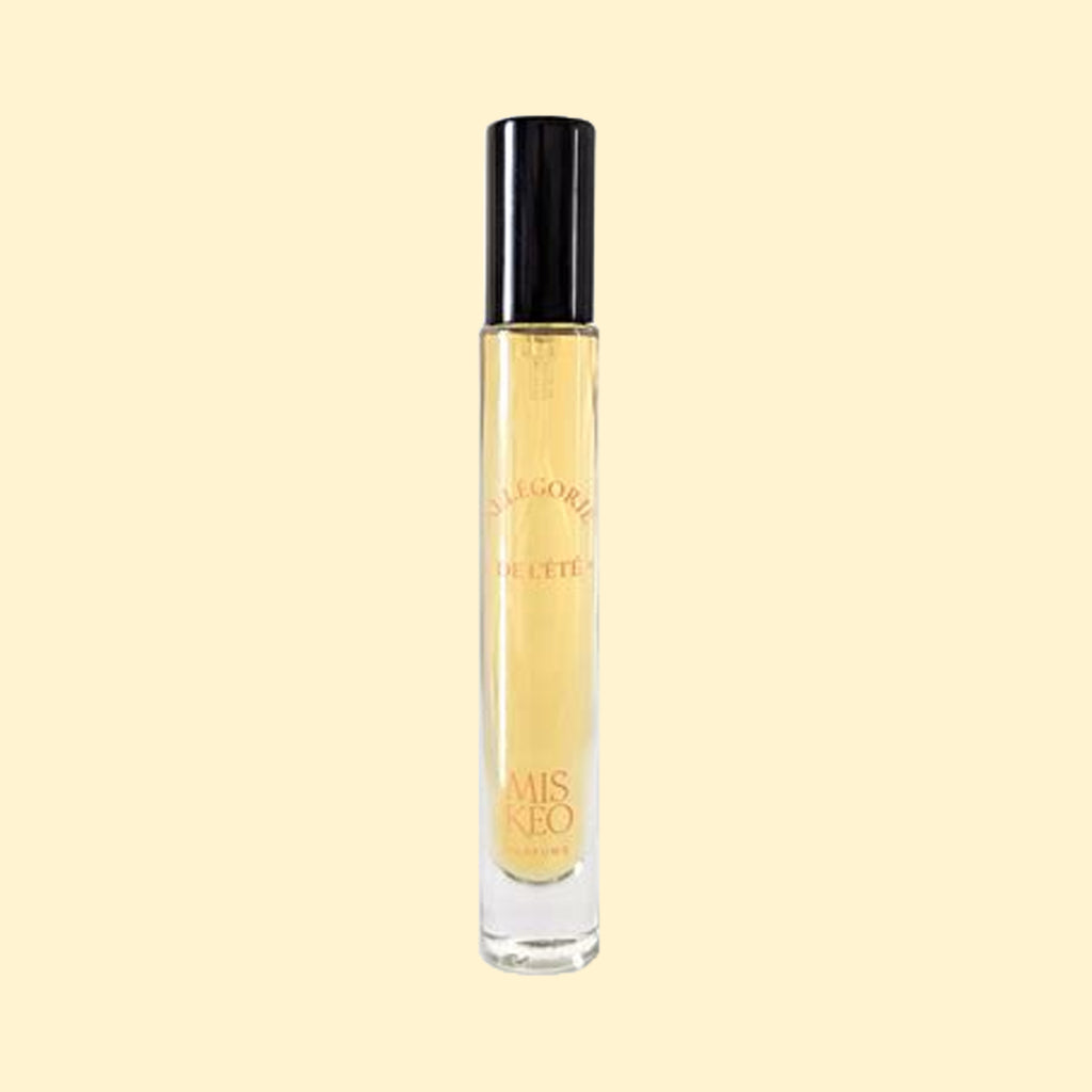 MISKEO Parfums Allégorie de l'Été Eau de Toilette in a slim clear glass travel spray bottle with a glossy black cap. The pale golden fragrance is presented against a soft beige background, highlighting the minimalist design and warm summer-inspired aesthetic.
