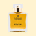 Papillon Artisan Perfumes Salome Eau de Parfum in a clear rectangular glass bottle with a white cap and gold collar, filled with warm golden-amber fragrance against a soft cream background.
